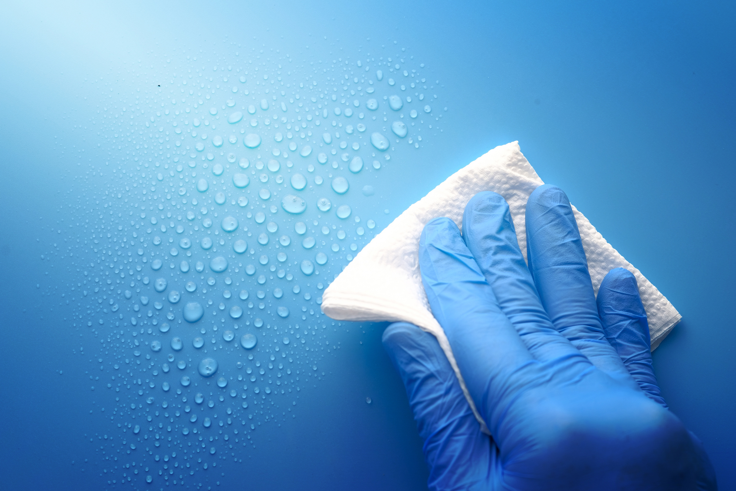 Hand in Blue Rubber Gloves Cleaning Table with Cloth